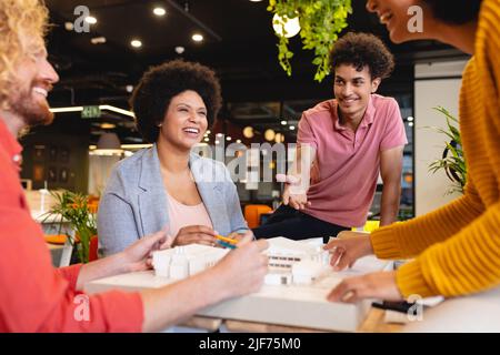 Smiling multiracial male and female architects discussing over architectural model in office Stock Photo