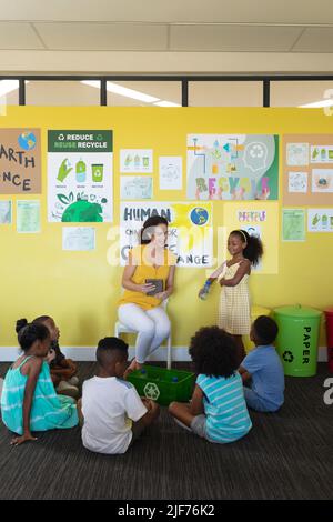 Female teacher teaching importance of recycling to multiracial students in classroom, copy space Stock Photo