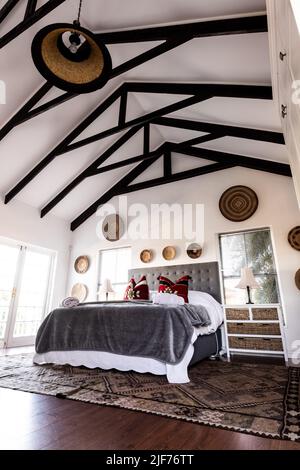 Bed with blankets and pillows and decorations hanging on mansard roof and wall in modern bedroom Stock Photo