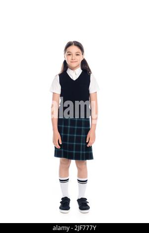 Full length of smiling schoolkid in plaid skirt standing on white background Stock Photo