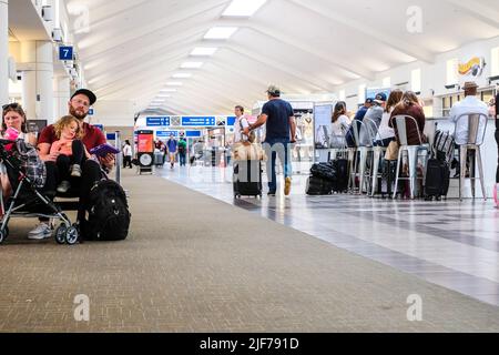 Flight cancellations stress weary travelers. Stock images of current flight delays around the USA. Passengers waiting at gate. Airport concourse. Stock Photo