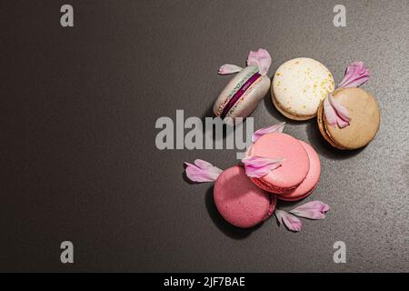 Macarons with peony flower on a black stone background. Sweet dessert, colorful and pastel colors. Romantic style, festive card, flat lay, hard light, Stock Photo