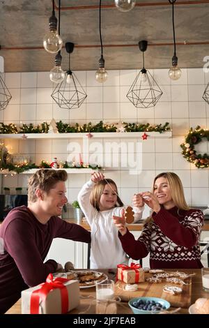 Happy parents and child daughter making Christmas cookies at home. Stock Photo