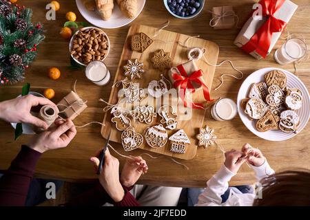 Top view of family and kid daughter making family xmas tree holiday decorations. Stock Photo