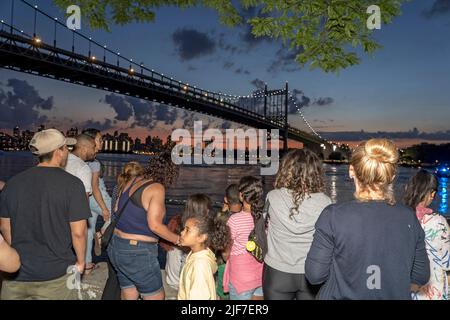 NEW YORK, NY - JUNE 29: Spectators gather for the Central Astoria annual Independence Day Celebrations fireworks display in Astoria Park on June 29th, 20221 in the Queens borough of New York City. Stock Photo