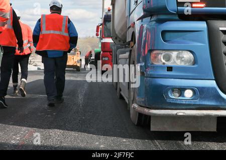 working team at road construction site wearing safety vests-building, teamwork, partnership, people Stock Photo