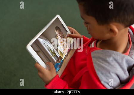 High angle view of biracial boy looking at friend through video call on digital tablet screen Stock Photo