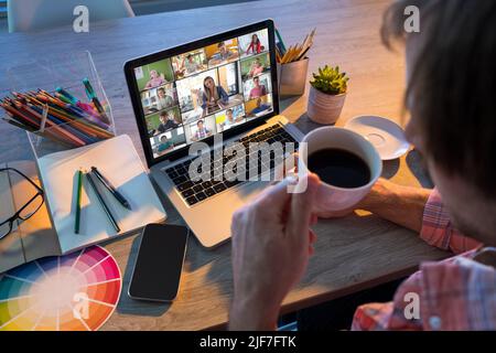 High angle view of caucasian male teacher having black coffee while teaching online over laptop Stock Photo