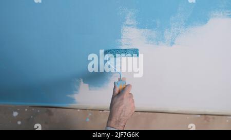 Man paints white wall with blue dye closeup Stock Photo