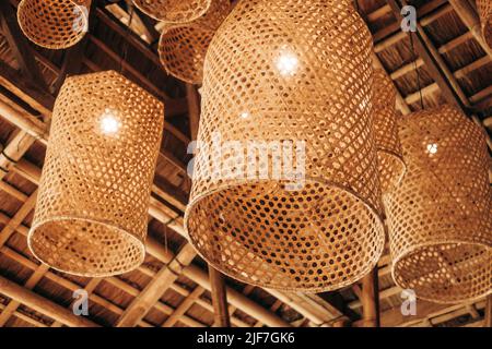 Hanging hand woven bamboo baskets, under cogon roof, made into light or lamp shades for decoration and ambience. Selective focus. Stock Photo