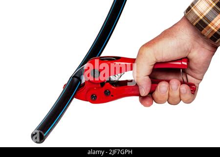 Plumber tools isolated. A man accurately cuts a piece of PE pressure pipe or water pipe with a red pvc pipe cutter. Clipping path. Drinking and servic Stock Photo