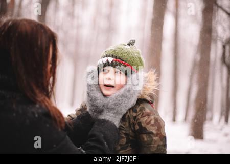 Baby boy looking at mother while she holding his face in winter Stock Photo