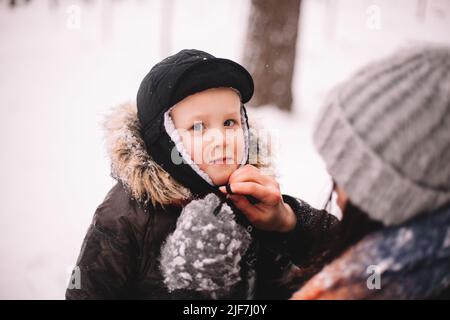 Happy baby boy looking at camera standing by his mother outdoors Stock Photo