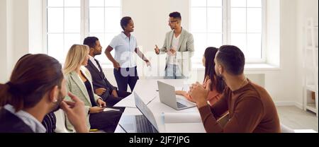 Friendly business team in positive atmosphere discuss working issues during working meeting. Stock Photo