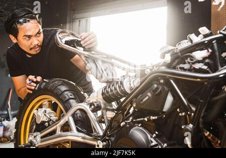 mechanic working on motorcycle at custom bike shop in Bangkok Stock Photo