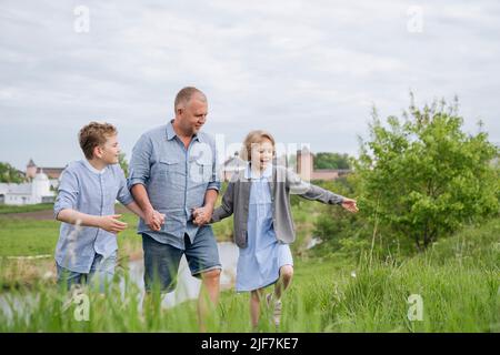 A father and his children are having fun talking on a walk. Stock Photo