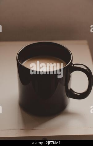 vertical black mug with creamy latte Stock Photo