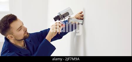 Professional technician installing surveillance CCTV camera on wall inside the building Stock Photo