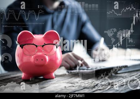 Close-up Of Businessperson With Piggybank Calculating Tax At Desk Stock Photo