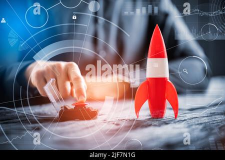 Businessman's Hand Launching Rocket By Pressing Red Button Stock Photo