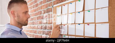 Close-up Of A Businessman Looking At Notes Attached On Bulletin Board Stock Photo