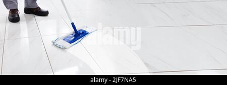Worker Mopping Floor With Mop In Kitchen Stock Photo