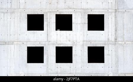 Six empty square windows, black window holes on a grey raw concrete wall, unfinished building side view, detail, frontal, front view, nobody. Building Stock Photo