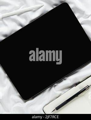 Flat lay top view blank screen digital tablet on white bed. Home office workspace Stock Photo