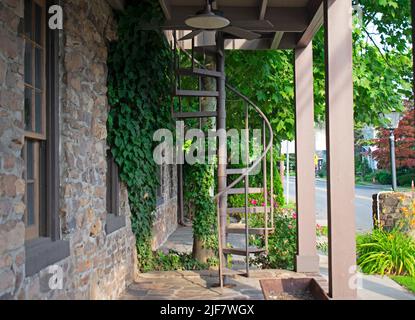 Looking through a portico at an outdoor spiral staircase next to a stone wall -02 Stock Photo