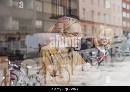 Young computer programmers sitting in office seen through glass window Stock Photo