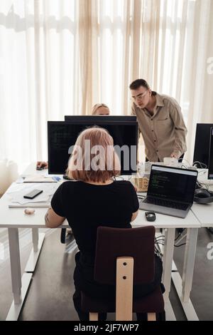 Businesswoman using computer at desk while colleagues discussing in office Stock Photo