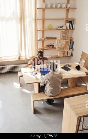 Male programmers discussing while sitting at desk in tech start-up office Stock Photo