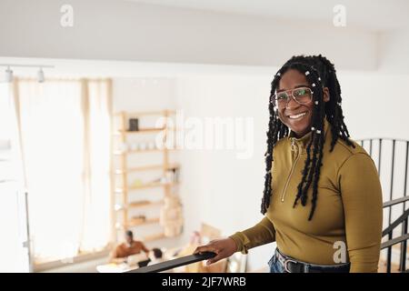 Portrait of smiling female computer programmer standing by railing at tech start-up office Stock Photo