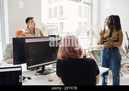 Female programmer giving presentation to colleagues during meeting in office Stock Photo