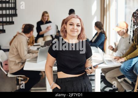 Portrait of young female entrepreneur with hand in pocket holding digital tablet at office Stock Photo