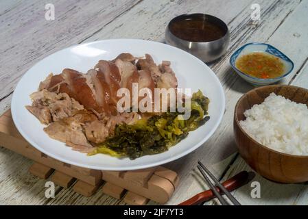 Stewed pork leg with pickled mustard. Boiled pork knuckle with chinese herbs. served with Thai style pickled chillies in vinegar Stock Photo