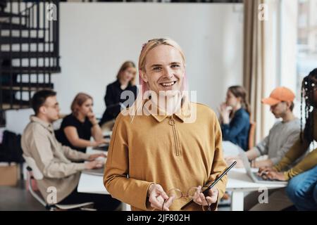 Portrait of smiling computer programmer holding digital tablet and eyeglasses at office Stock Photo