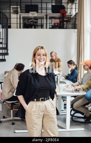 Portrait of confident businesswoman with hands in pocket standing at tech start-up office Stock Photo