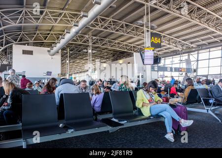 Brussels airport waiting room - Passenger before the departure - People are waiting to access the plane sitting in  the waiting area | Les gens attend Stock Photo
