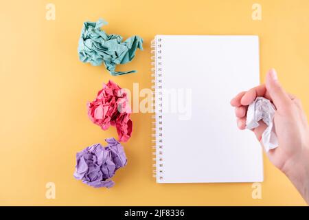 the hand crumpling the page of the notebook on a yellow background. space for text. turning over a new leaf Stock Photo