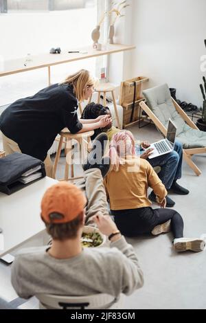 Young computer programmers discussing over laptop while businessman eating lunch at office Stock Photo