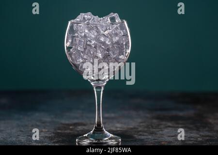 Glass full of ice standing on a table in the dark Stock Photo