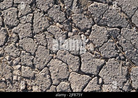 Close-up of cracked asphalt texture. Cracks on the old road surface. Stock Photo