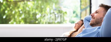 Smiling Young Couple Relaxing Sitting On Couch At Home Stock Photo