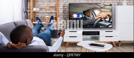 Man Lying On Sofa Watching Television At Home Stock Photo
