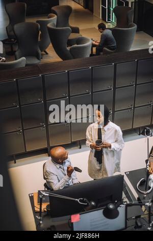 Young businesswoman discussing with male colleague sitting at desk in office Stock Photo