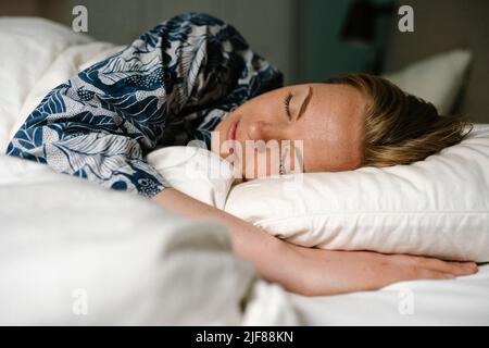 Woman sleeping on bed in bedroom at home Stock Photo