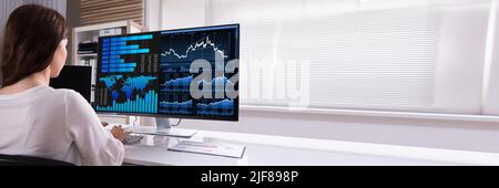 Female Stock Market Broker Analyzing Graphs On Computer At Workplace Stock Photo