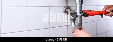 Close-up Of A Plumber's Hand Repairing Sink With Adjustable Wrench Stock Photo