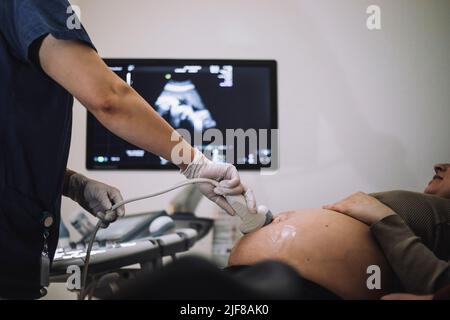 Female gynecologist doing ultrasound of pregnant woman in hospital Stock Photo